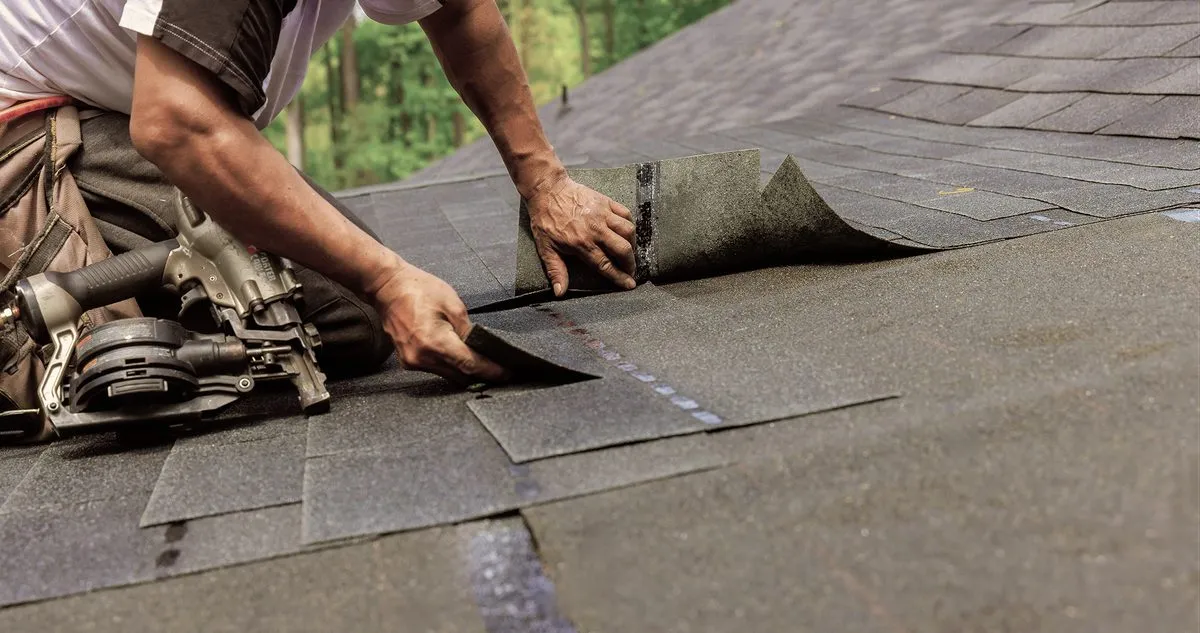 A roofer laying asphalt shingles