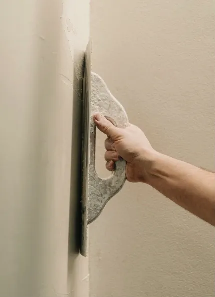Contractor smoothing a freshly plastered wall.